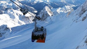 Eine Seilbahn fährt einen verschneiten Berghang hinauf.
