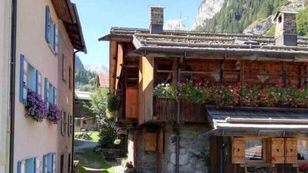 Ein traditionelles Chalet mit Natursteinfassade, Holzbalkonen und Blumenkästen.