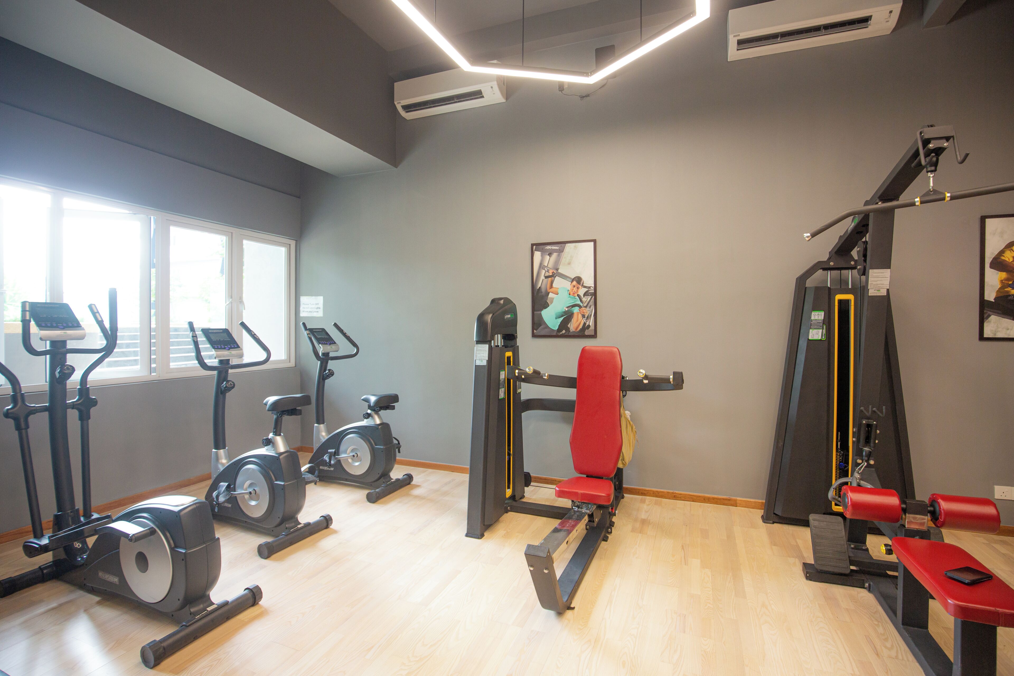 Un gimnasio con bicicletas estáticas, cinta de correr, banco de pesas y estructura para sentadillas.