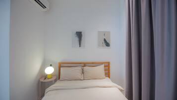 A bedroom with a bed, a nightstand with a lamp, and two wall-mounted pictures.