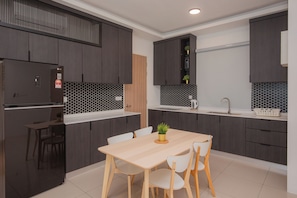 A modern kitchen with dark cabinets, a wooden table, and white chairs.