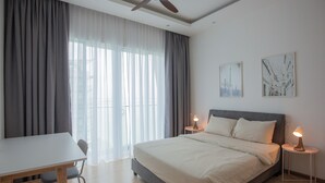 A modern bedroom with a large bed, a desk, and two bedside lamps. - QuayWest (George Town)