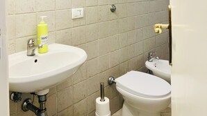 Une salle de bain avec deux lavabos, des toilettes, un miroir et une pomme de douche.