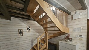 A wooden spiral staircase in a room with white wooden walls and a white cabinet. - Comfortable Holiday Home With a Terrace and Garden (Karsin)
