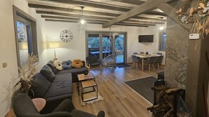 A modern living room with a sofa, chairs, a dining table, a TV, and a fireplace. - Comfortable Holiday Home With a Terrace and Garden (Karsin)
