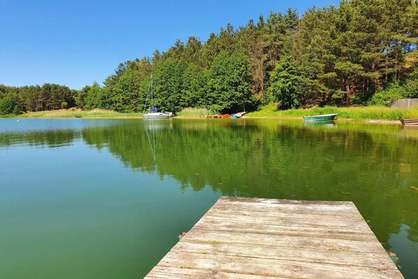 A calm lake with a wooden dock extending into the water, surrounded by dense forest. - Comfortable Holiday Home With a Terrace and Garden (Karsin)