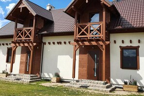 A two-story house with a gabled roof, wooden balconies, and a stone foundation. - Comfortable Holiday Home With a Terrace and Garden (Karsin)