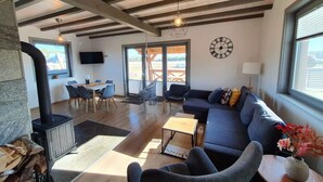 A spacious living area with a fireplace, a sofa, a dining table, and a large window. - Comfortable Holiday Home With a Terrace and Garden (Karsin)