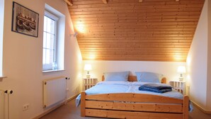 Ein Schlafzimmer mit Holzboden, einem Einzelbett, zwei Nachttischlampen, einem Fenster und einer Heizung.