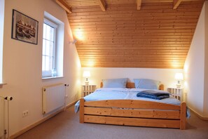 Ein Schlafzimmer mit Holzboden, einem Einzelbett, zwei Nachttischlampen, einem Fenster und einer Heizung.