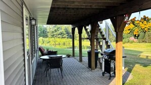 Un patio couvert équipé d’un barbecue, de meubles d’extérieur et de jardinières suspendues.
