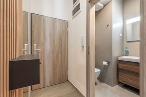 Un baño moderno con tocador de madera, inodoro y espejo.
