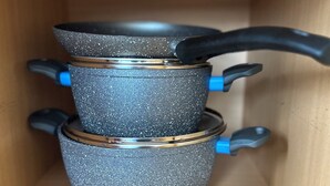 Ein Holzschrank mit drei gestapelten Kochutensilien.