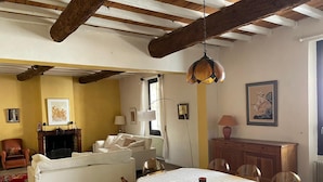 A cozy living room with a fireplace, white sofa, dining table, and chairs. - 19th-century farmhouse combining authenticity and comfort (Gallargues-le-Montueux)