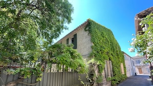 A narrow street with a building covered in ivy, a metal gate, and a clear blue sky. - 19th-century farmhouse combining authenticity and comfort (Gallargues-le-Montueux)