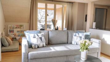 Ein modernes Wohnzimmer mit einem grauen Sofa, einem kleinen runden Tisch und einem Blumenstrauß.
