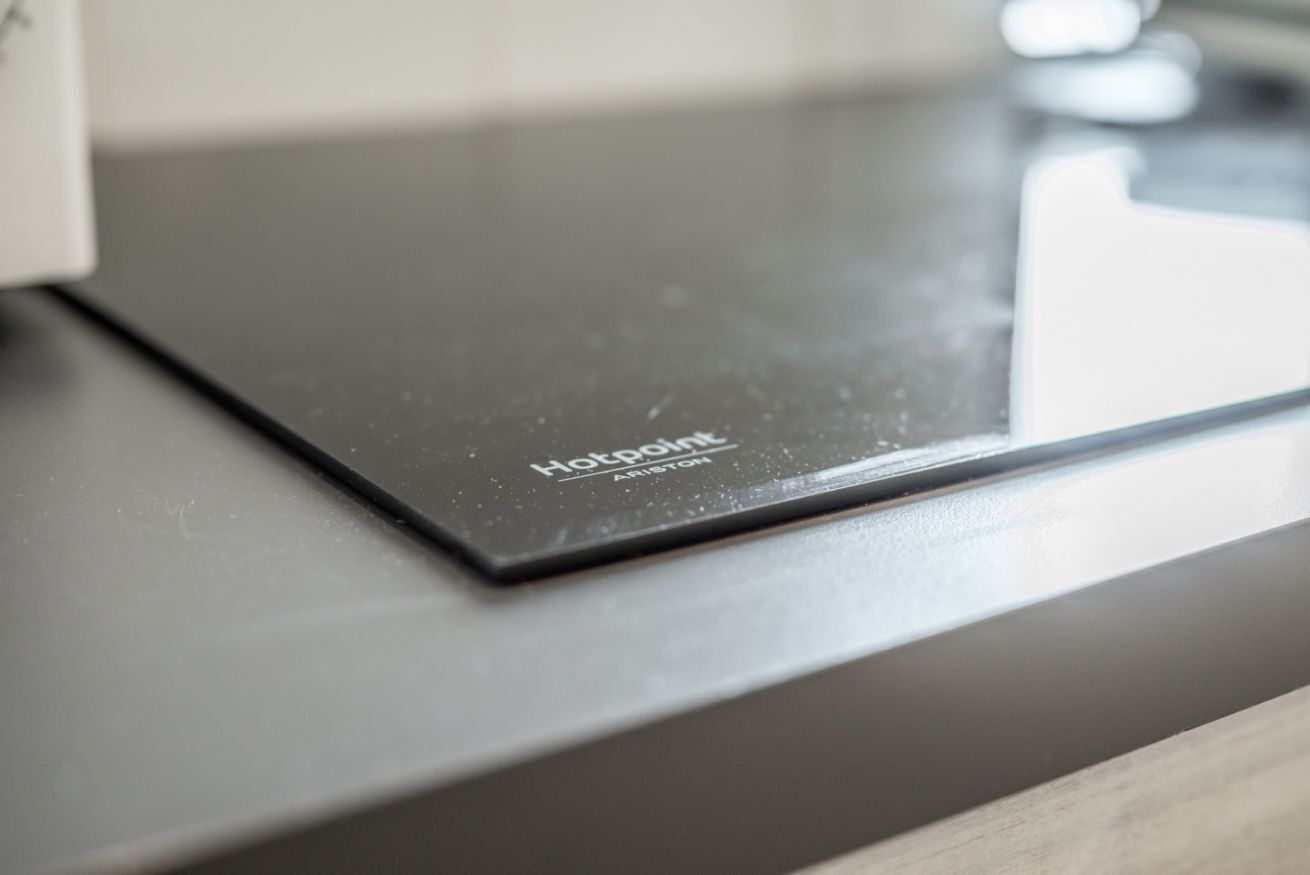 A kitchen countertop with a black induction cooktop labeled "Hotpoint."