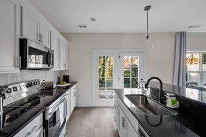 A modern kitchen with white cabinets, stainless steel appliances, and a large window with a view of greenery. - 1 King 2 Queens Garage Yard Washer Dryer (Old Hickory)