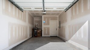 Un garage avec une porte de garage fermée, une porte à l’extrémité et un sol en béton.
