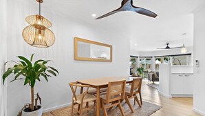 Een eethoek met een houten tafel en stoelen, een potplant en een hanglamp.