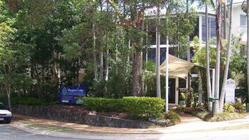 A Macquarie Lodge reception area with a sign, a covered outdoor seating area, and lush greenery.