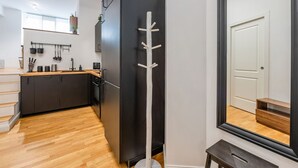 Une cuisine moderne avec des meubles de couleur sombre, un plancher en bois et un réfrigérateur noir.
