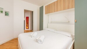 Une chambre d’hôtel moderne avec un grand lit, une tête de lit en bois et une petite table de chevet.