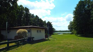 A house with a fenced yard and a view of a lake. - Bungalow in Schlowe Am See (Borkow)