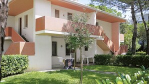 Un bâtiment à deux étages, doté d’un toit plat, d’une entrée centrale et d’un petit patio aménagé avec des sièges extérieurs.