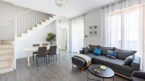 Uma sala de estar moderna com escada, área de jantar e sofá com almofadas.