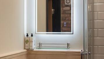 Une salle de bain avec un lavabo, un miroir et une douche.