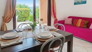 Un coin repas avec une table dressée pour deux personnes, un canapé et un tableau accroché au mur.