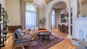 A spacious living room with a large orange sofa, a wooden coffee table, and a chandelier. - Downtown Glass & Glory Heritage Stay (Cairo)