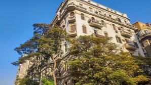 A multi-story building with balconies, large windows, and a tree in front. - Downtown Glass & Glory Heritage Stay (Cairo)