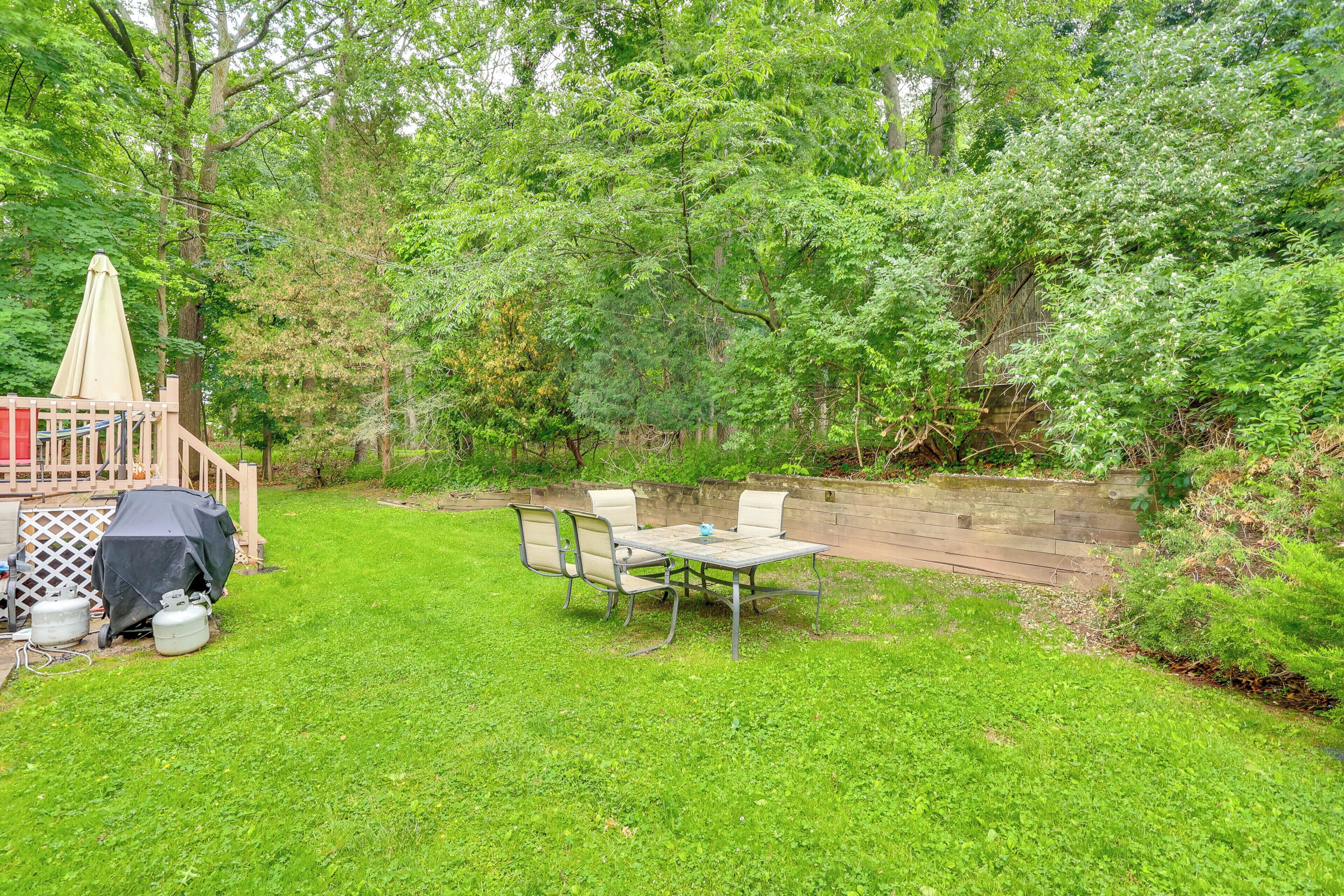 A backyard with a wooden deck, a covered grill, and a table with chairs.