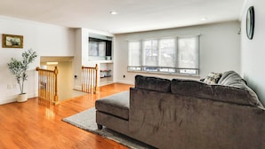 A living room with a grey sofa, wooden flooring, a staircase, and a window with blinds. - 26 Mi to Metlife & Nyc: 1 mi to Train (Scotch Plains)