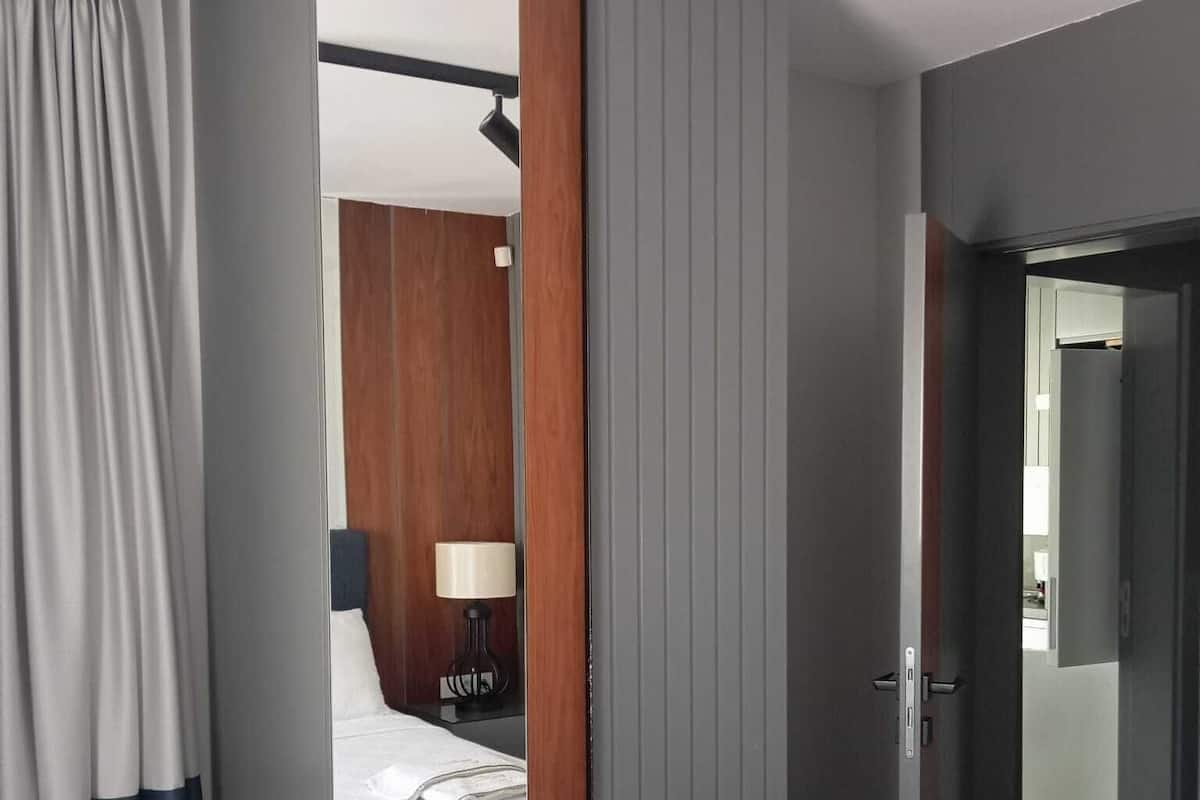Ein Hotelzimmer mit Bett, Nachttisch mit Lampe und Kleiderschrank.