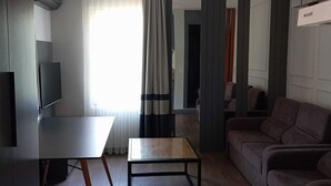 A modern living room with a flat-screen TV, a wooden coffee table, a sofa, and a dining area with a table and chairs. - EBRU EVLERI ICMELER MERKEZE PLAJA YAKIN (Marmaris)