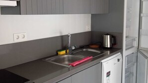 A kitchen with grey cabinets, a stainless steel sink, a kettle, and a microwave. - EBRU EVLERI ICMELER MERKEZE PLAJA YAKIN (Marmaris)