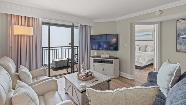 Ein modernes Hotelzimmer mit Balkon, Flachbildfernseher, Essbereich und Schlafbereich.