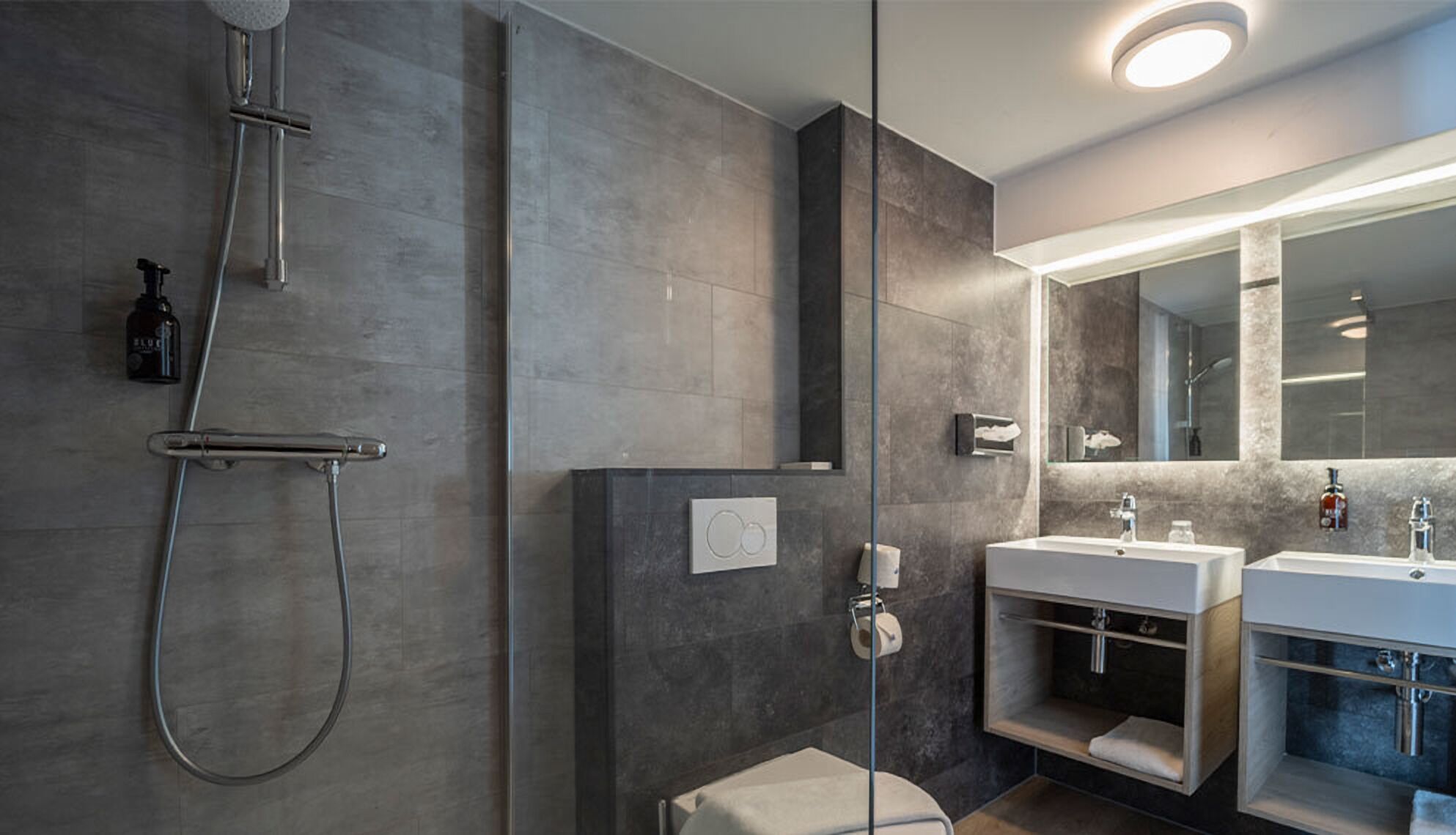 A modern bathroom with a walk-in shower, a large mirror, and a vanity with a sink.