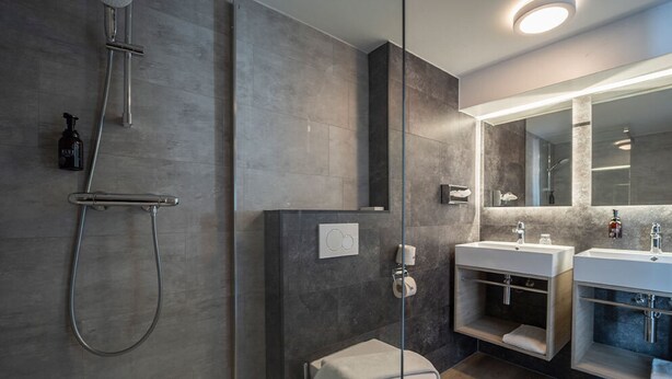 Un baño moderno con cabina de ducha, un espejo grande y un mueble de tocador con lavabo.