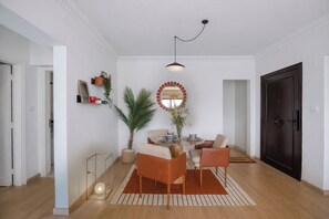 A modern dining area with a round table, two chairs, a hanging light fixture, and a decorative mirror on the wall.