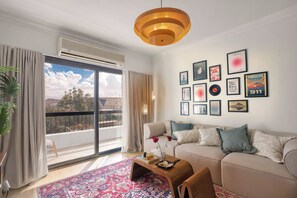 A modern living room with a sofa, a coffee table, and a large window with curtains.