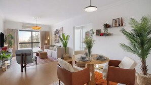 A modern living room with a dining area, a sofa set, and a large window with curtains.