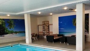 A swimming pool with a view of palm trees and a sunset mural. - Scenic Room Near Nijmegen Perfect for Family Adventures! Indoor Pool, Parking! (Berg en Dal)