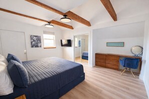 Ein Schlafzimmer mit einem Bett, einem Schreibtisch, einem Stuhl, einem Spiegel und einem Fernseher.