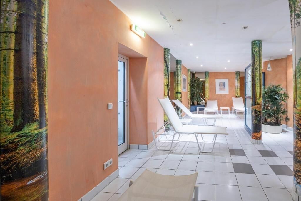 A hotel lobby with a checkered floor, white lounge chairs, and a glass partition wall.