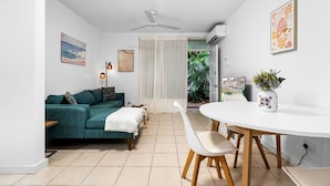 A modern living room with a teal sofa, a white dining table with wooden chairs, and a ceiling fan. - Zen Bamboo Cozy - Modern - Central (Darwin)
