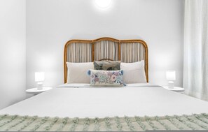 Quarto bem arrumado com uma cama, duas mesas de cabeceira e um criado-mudo.